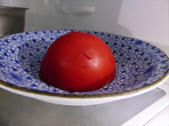 半分に切ったトマト、切り口を下にして冷蔵庫で保管している様子